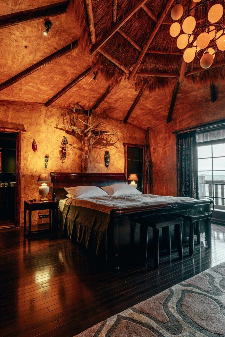 Hotel Rangá Africa Master Suite featuring a thatched roof and traditional artwork including a tree hanging above the King bed.