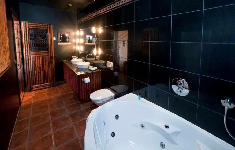 Hotel Rangá Africa Suite bathroom decorated with black tiles, wooden accents and a large bathtub.