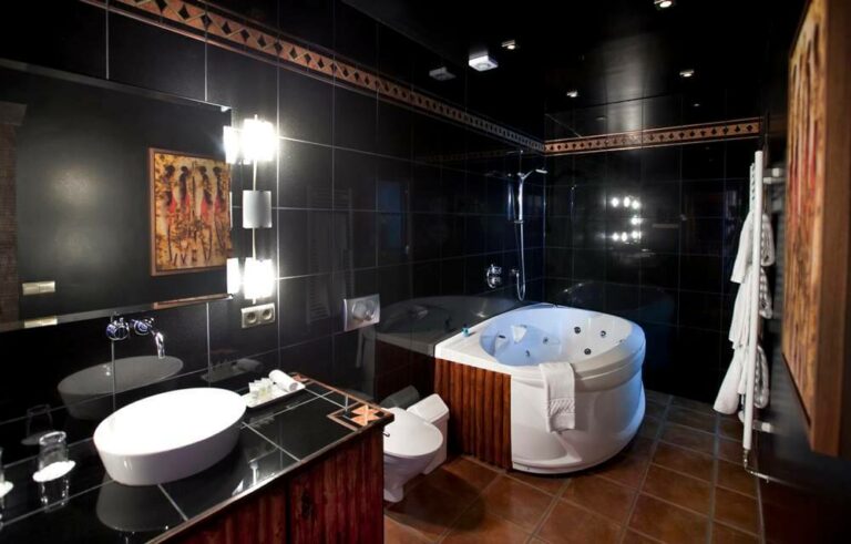 Bathroom in the Hotel Rangá Africa suite decorated with black tiles, wooden accents and a large, soaking tub.
