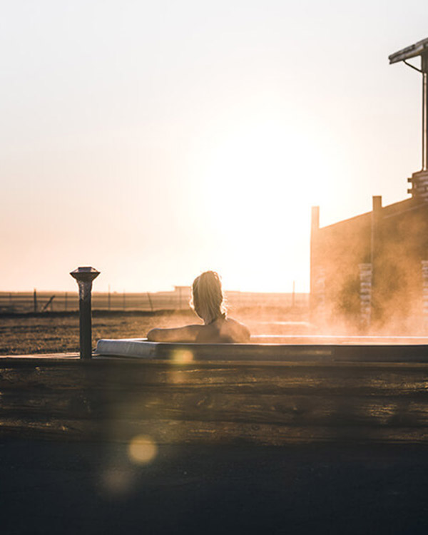 Woman lounges in a Hotel Rangá geothermal hot tub as the sun shines on her.