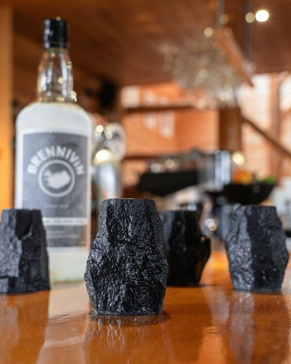 Lava shot glasses made of Icelandic columnar basalt and a bottle of ice cold Brennivín liquor on the Rangá Bar.